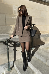 a lady in a black top, a brown blazer and a brown skirt